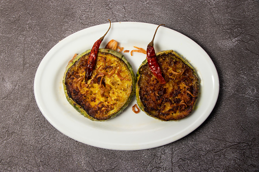 Begun Bhaji or fried eggplant served in dish isolated on background top view of bangladesh food