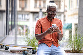African American man with bleached hair using smart phone in the city