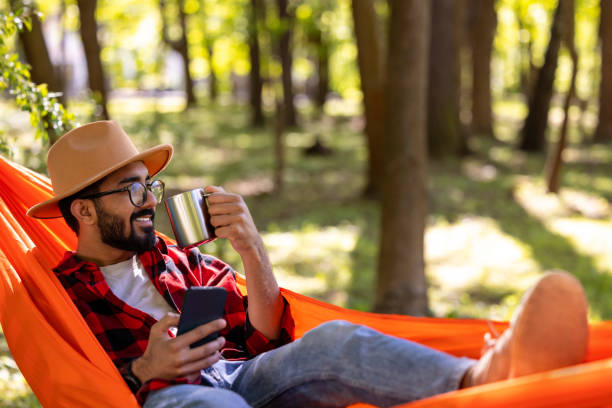 istock Bearded young man in s straw hat feeling relaxed in hammock 1607474745