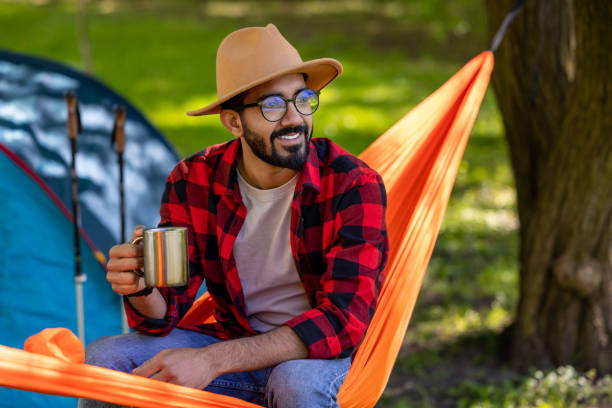 istock Smiling man with cup in hands enjoying nature in a hammock 1607474988