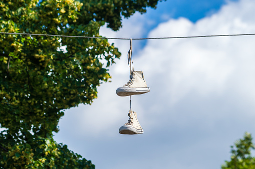 White sneakers hanging on wires against the sky