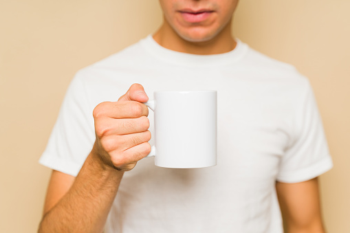 Caucasian man drinking coffee using a 11 oz white mug and mock-up t-shirt for a product design