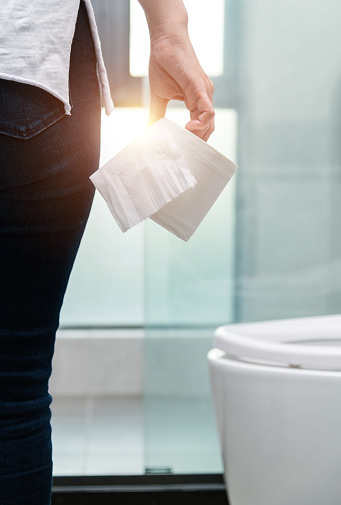 Woman holding toilet paper in toilet.