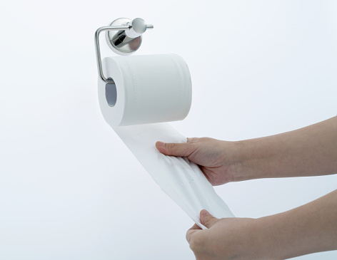 Woman hand pulling toilet paper.