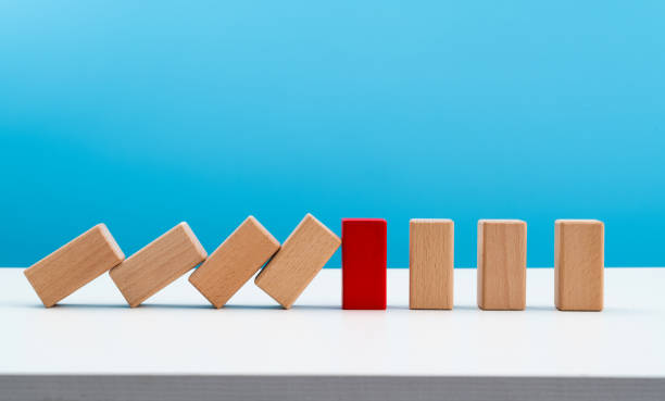 istock Red wooden block stop other falling dominos 1607506653