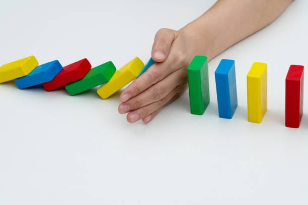 istock Woman hand stopping the dominos falling 1607508733
