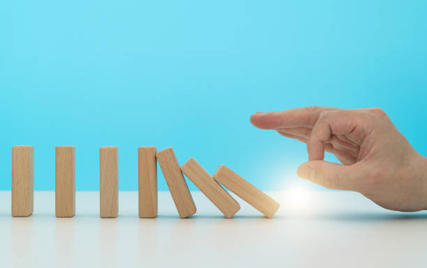istock Human finger pushing domino pieces 1607509120