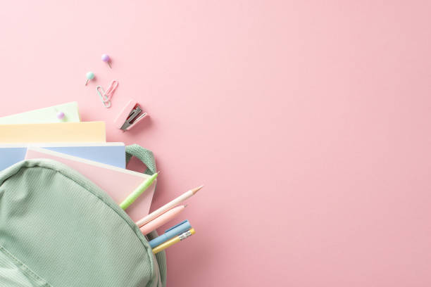 istock Schoolgirl's delight: Top view of open sage backpack with pencils, pens, notebooks, mini stapler, pushpins and clips for upcoming school season. Advertise in the pink pastel backdrop 1607535456