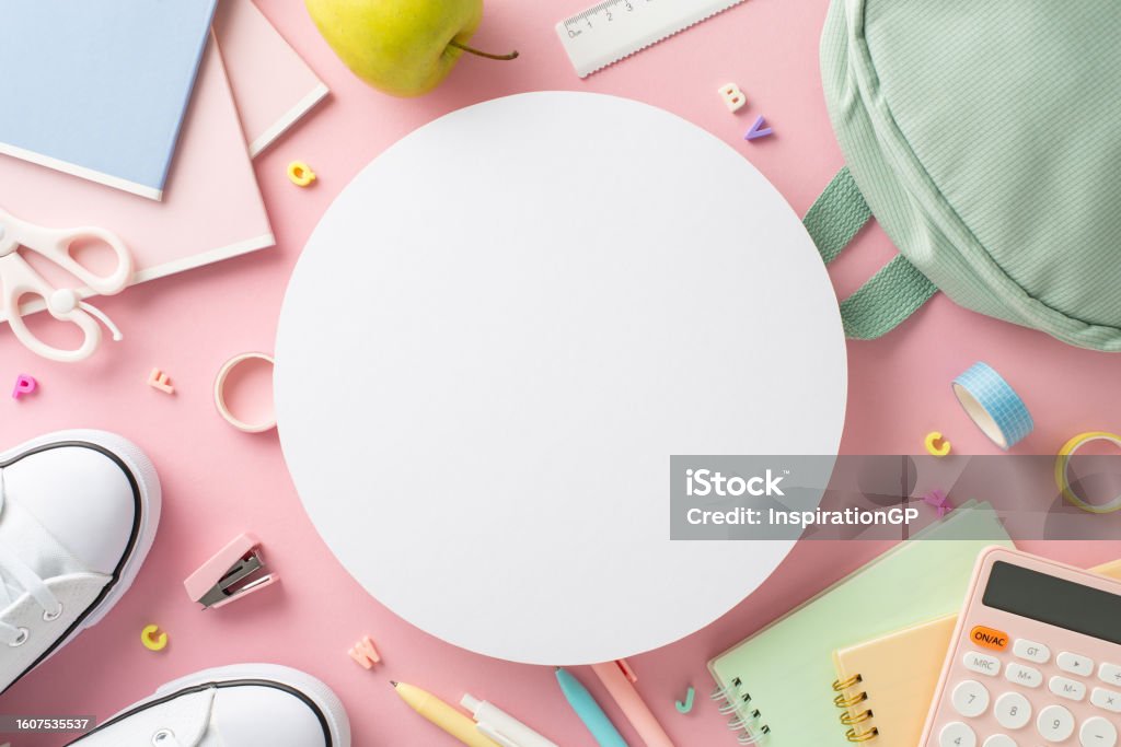 Stylish girly school equipment scene. Top view of stationery, bag, pens, ruler, adhesive tape, scissors, diaries, alphabet letters and more on pastel pink background, empty circle for text or ad Advertisement Stock Photo