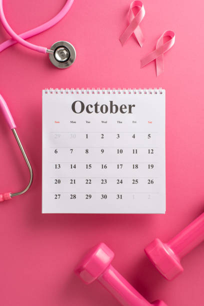 Advocating Breast Cancer Awareness Month. Bird's-eye top vertical view of a calendar, stethoscope, weights and pink ribbon on a bright pink isolated background, with copyspace for text or promotions abogando por el mes de concientización sobre el cáncer de mama. vista vertical superior a vista de pájaro de un calendario, estetoscopio, pesas y cinta rosa sobre un fondo aislado de color rosa brillante, con espacio de copia para texto o promociones