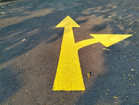Yellow arrow sign on asphalt background
