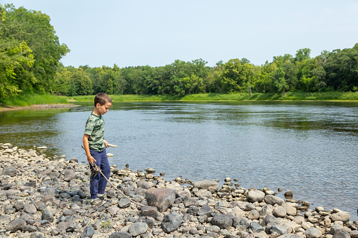 Young boy exploring the riverbed of the Mississippi River during a dry summer in Minnesota, USA.