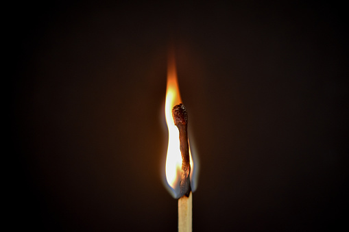 A flaming match stick flame in a dark room