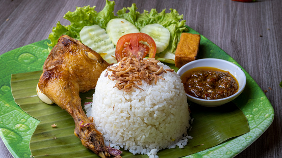 Grilled chicken thighs served with white rice, sambal, and fresh vegetables.