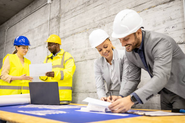 istock Team of experienced architects and civil engineers analyzing and looking at building plant at construction site. 1607565265
