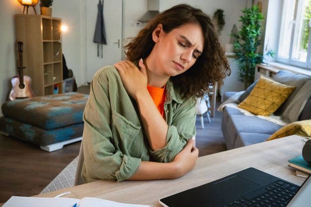 istock Female student experiencing a pain in her shoulder, while e-learning at home 1607576017