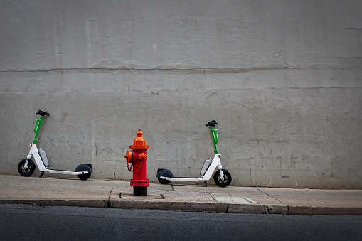 A sidewalk on a hill, with two scooters parked next to a fire hydrant, in Nashville, Tennessee.