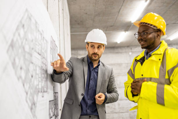 istock Construction engineer or architect presenting building plan and blueprint to the worker at the site. 1607587884