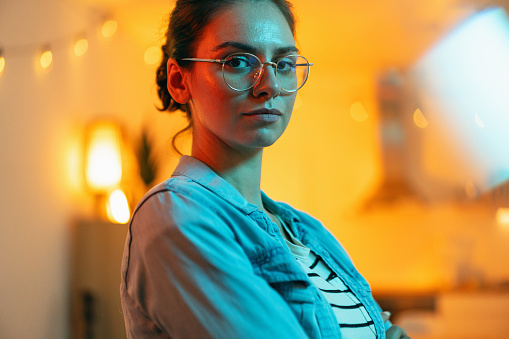 Portrait of a young confident and dedicated Caucasian woman, with orange/yellow light in the background