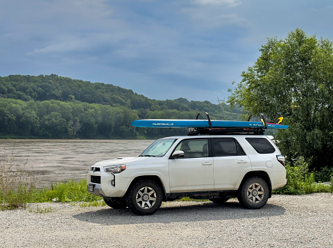 Rocheport, MO, USA - August 4, 2023: Toyota 4Runner SUV with a performance stand up paddleboard (Starboard Waterline) on roof racks on a shore of the Missouri River at Taylor's access boat ramp.