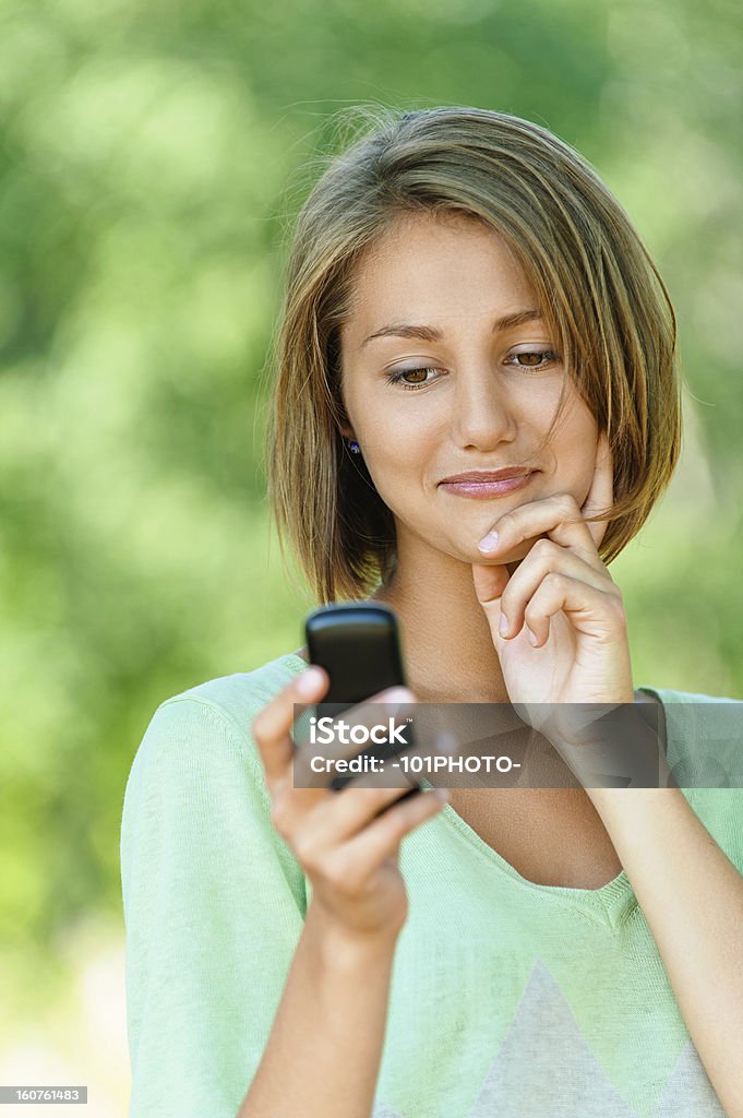 Mujer joven lee sms a un teléfono móvil - Foto de stock de Adulto libre de derechos