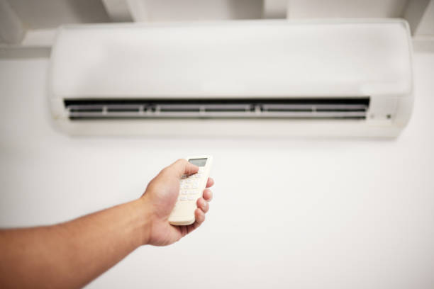 Air conditioner, hand and remote for electrical machine check with person in a home with ac repair. Maintenance, and system control for installation, inspection of aircon fix in house with contractor