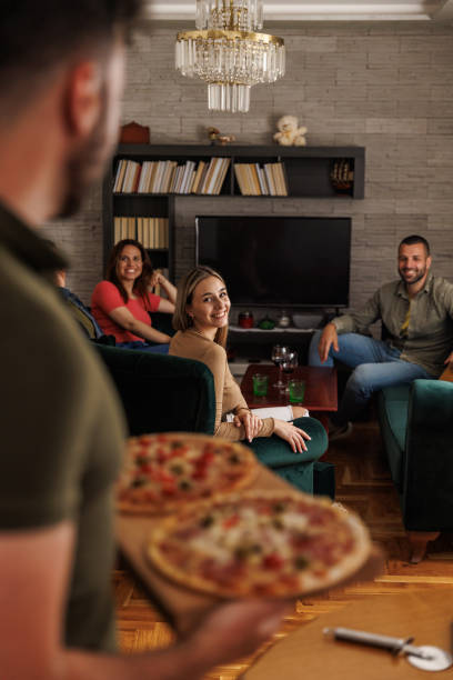 istock Man serving a board with two homemade pizzas for his friends 1607636335