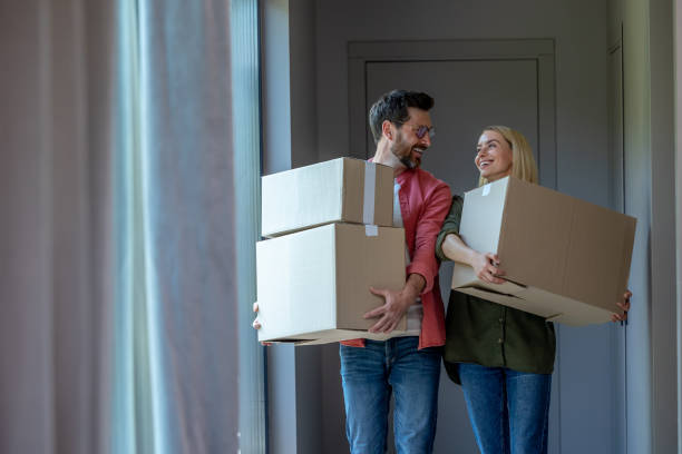 istock Young couple carrying cardboards with clothes while relocation 1607643843