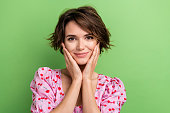 Photo of optimistic pretty nice woman with bob hairstyle dressed pink blouse hold palms on cheekbones isolated on green color background