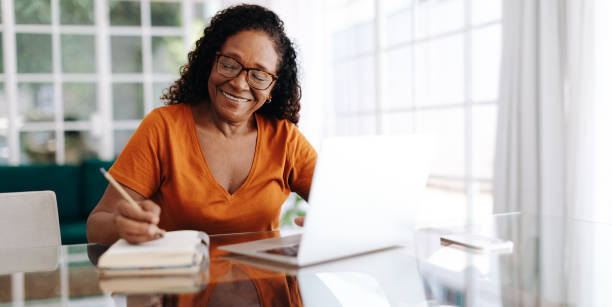 happy senior woman drafting her last will and testament in her journal - retirement planning imagens e fotografias de stock