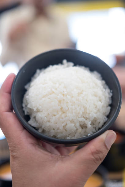 istock Hand holding a bowl with cooked rice 1607671457