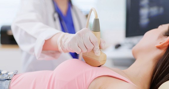 close up of asian doctor using ultrasound scanner performing examination of breast for her patient - cancer awareness feminine health medical concept