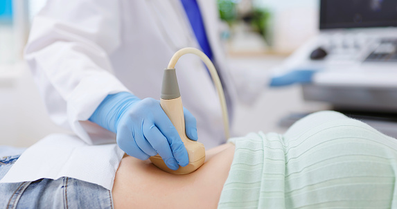 close up of asian doctor using ultrasound scanner performing examination of  belly for her patient - feminine health medical concept