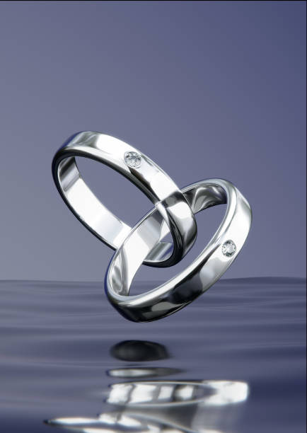 istock Two platinum diamond rings floating on the surface of the water in a studio scene. from design with 3D render. 1607706315