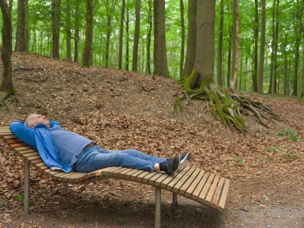 istock Senior man with wheelchair lying on bench relaxing in forest 1607716806