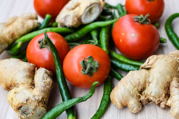 istock Fresh Ginger, Tomato and green chili pepper on plain wooden table, green essential vegetables for all essential foods, view of unpeeled vegetables with plain background 1607726542