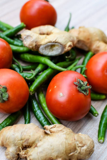istock Fresh Ginger, Tomato and green chili pepper on plain wooden table, green essential vegetables for all essential foods, view of unpeeled vegetables with plain background 1607726543
