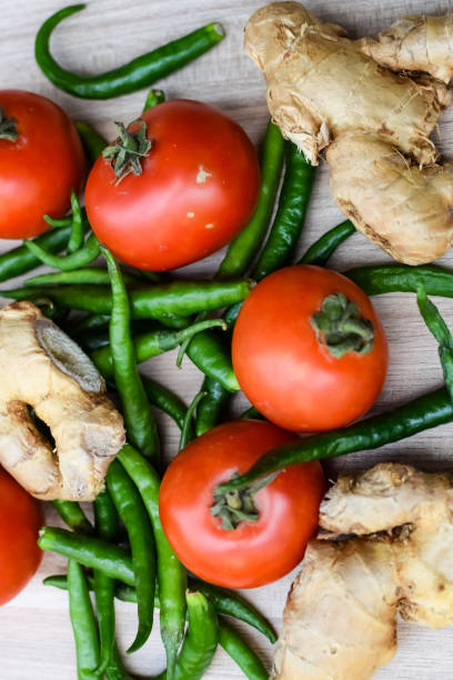 istock Fresh Ginger, Tomato and green chili pepper on plain wooden table, green essential vegetables for all essential foods, view of unpeeled vegetables with plain background 1607726551