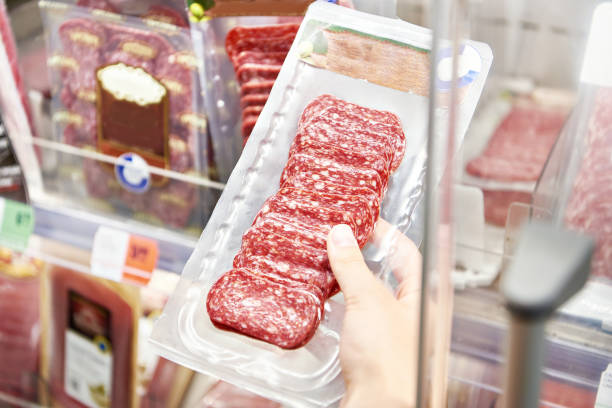 istock Sliced sausage in plastic pack in hands in store 1607728163