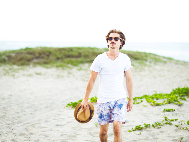 istock Handsome cool young gen z guy walking on the beach 1607759492
