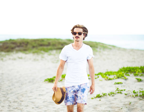 istock Handsome cool young gen z guy walking on the beach 1607760427