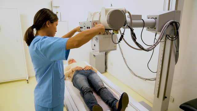 Female radiologist adjusting the machine while explaining the procedure to patient lying down