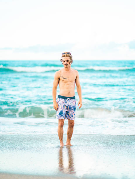 istock Handsome cool young gen z guy in swimsuit on the beach 1607777210