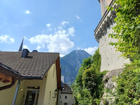 Beautiful houses in sunny summer day in Hallstatt town, Austria with mountain and blue sky clouds in background.