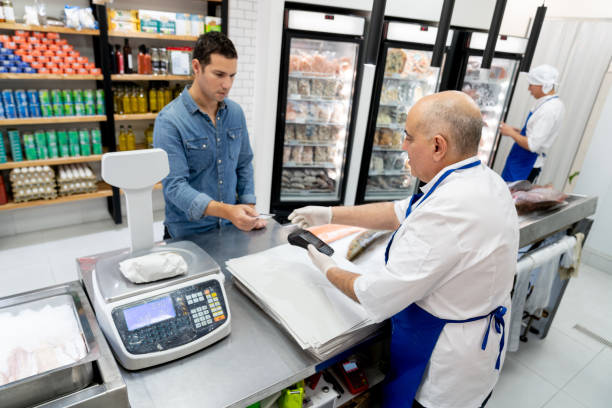 istock Handsome customer paying for his products using a credit card to mature fishmonger holding a credit card reader 1607786756
