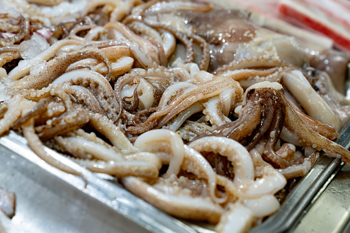 Close up fresh tentacles in an aluminum container at a seafood store - Small business concepts