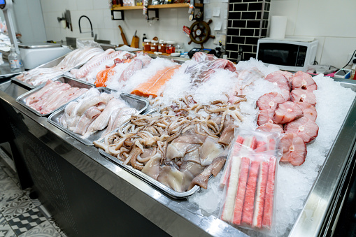 View of a fresh display cabinet with a variety of sea food in containers on ice - Small business concepts