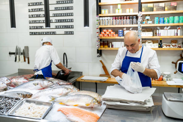 istock Male fishmongers working at a seafood store both looking focused 1607787337