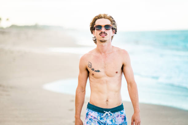 istock Handsome cool young gen z guy in swimsuit on the beach 1607798438