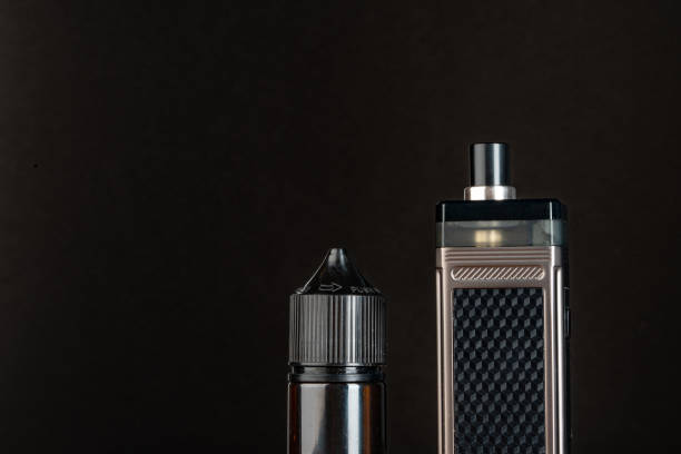 istock Vape and vape liquid bottles against black background 1607801724